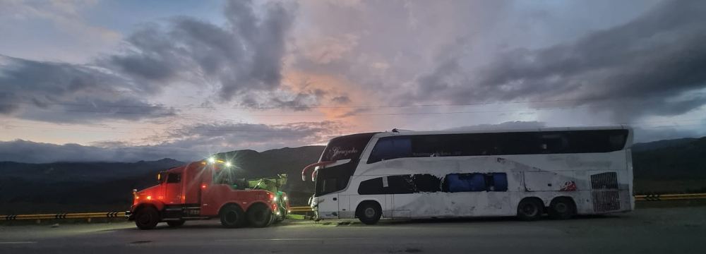 Grúa remolcando un bus al atardecer